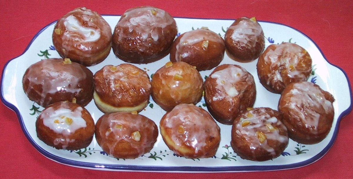 Homemade paczki. Decorated with icing and orange rinds