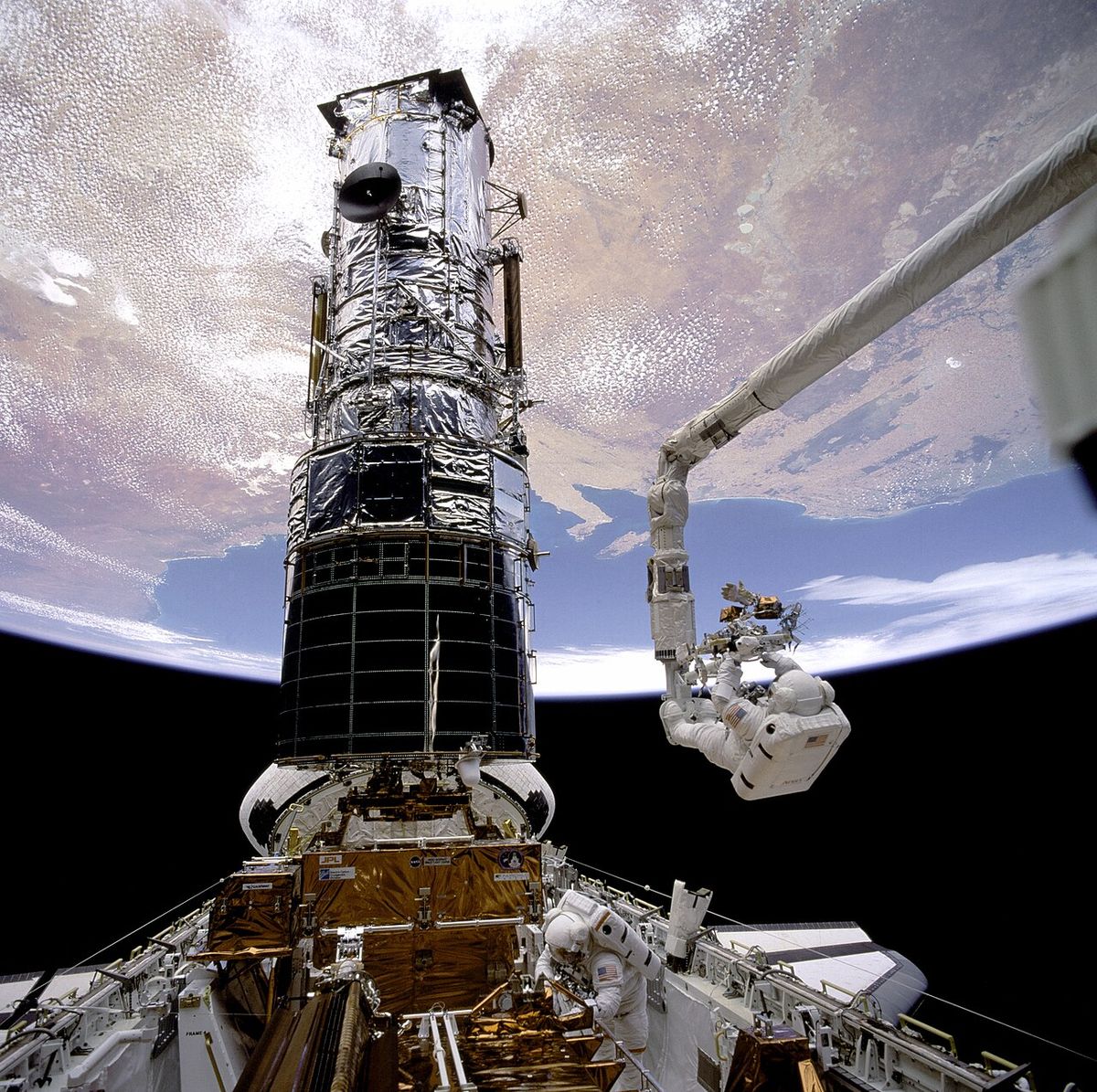 Astronaut F. Story Musgrave, anchored on the end of the Remote Manipulator System (RMS) arm, prepares to be elevated to the top of the Hubbl